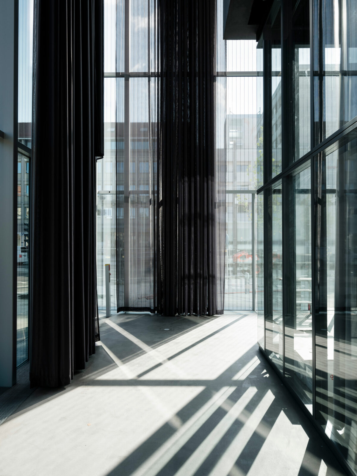 Glassfassade des Museums von Innen mit langen Vorhängen.