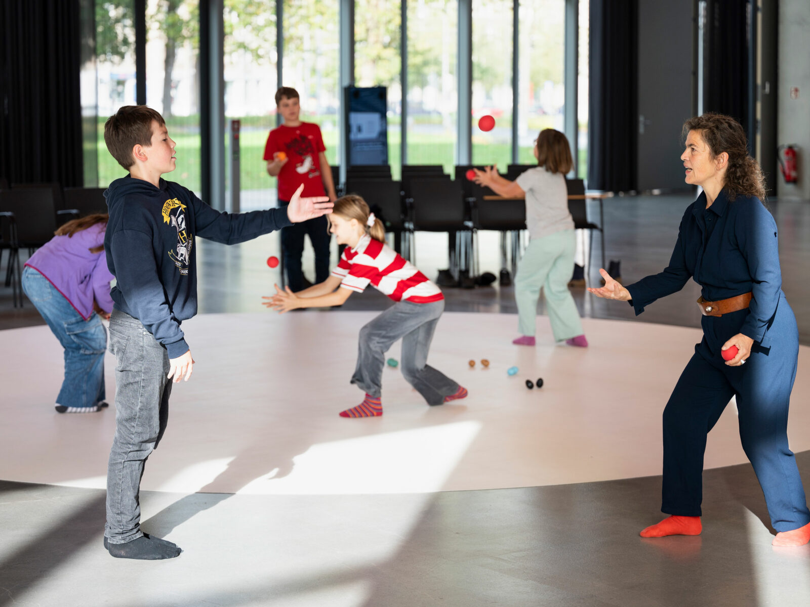 Several children and the workshop leader throw balls at each other.