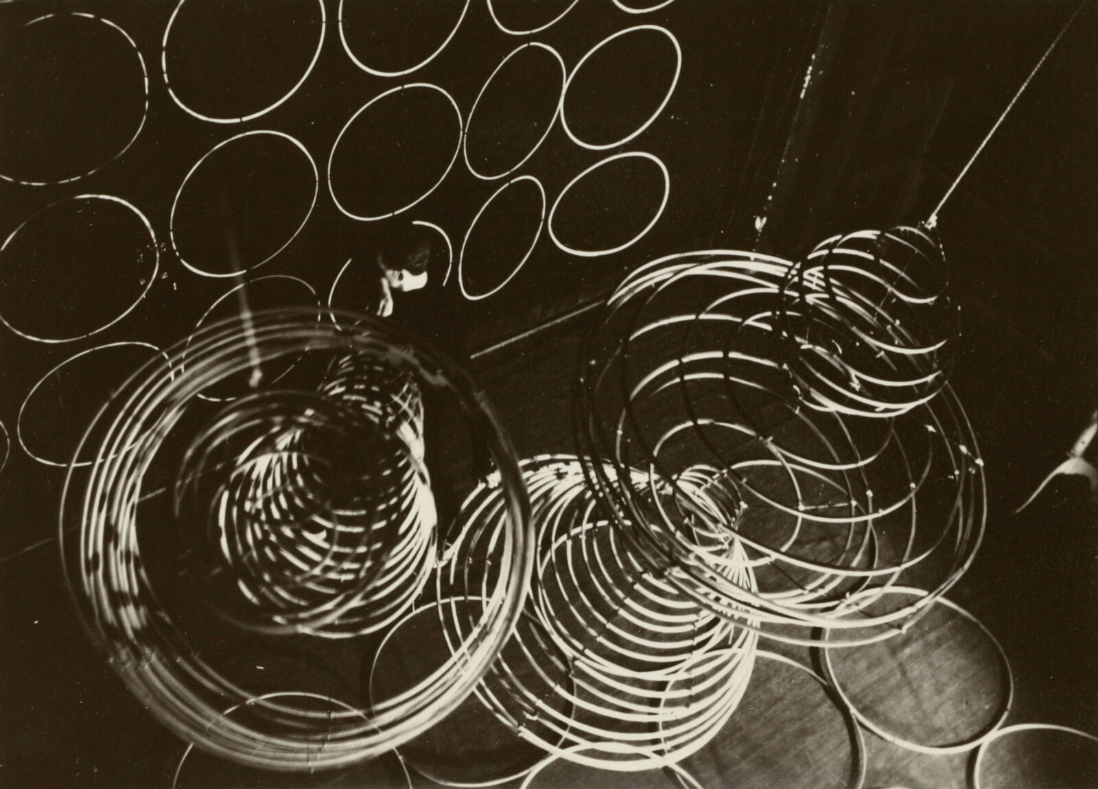 Historisches Schwarz-Weiß-Bild zeigt den Aufblick auf einen Tänzer, der umgeben ist von vielen großen Reifenspiralen.